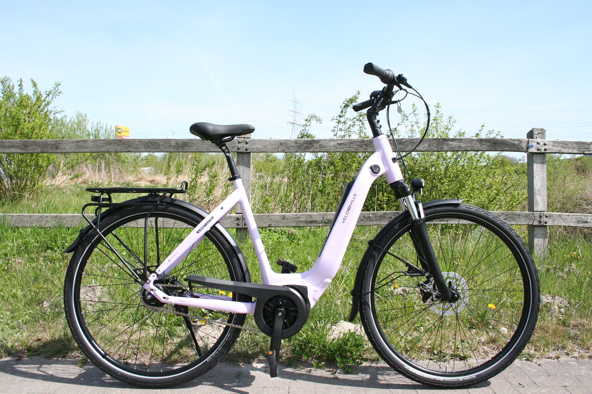 Symbolbild Velo de Ville E-Bike Westwind Smart bei Rückenwindräder in Wilhelmshaven: ein E-Bike der Marke Velo de Ville in Weiß auf einem gepflasterten Weg vor grüner Natur